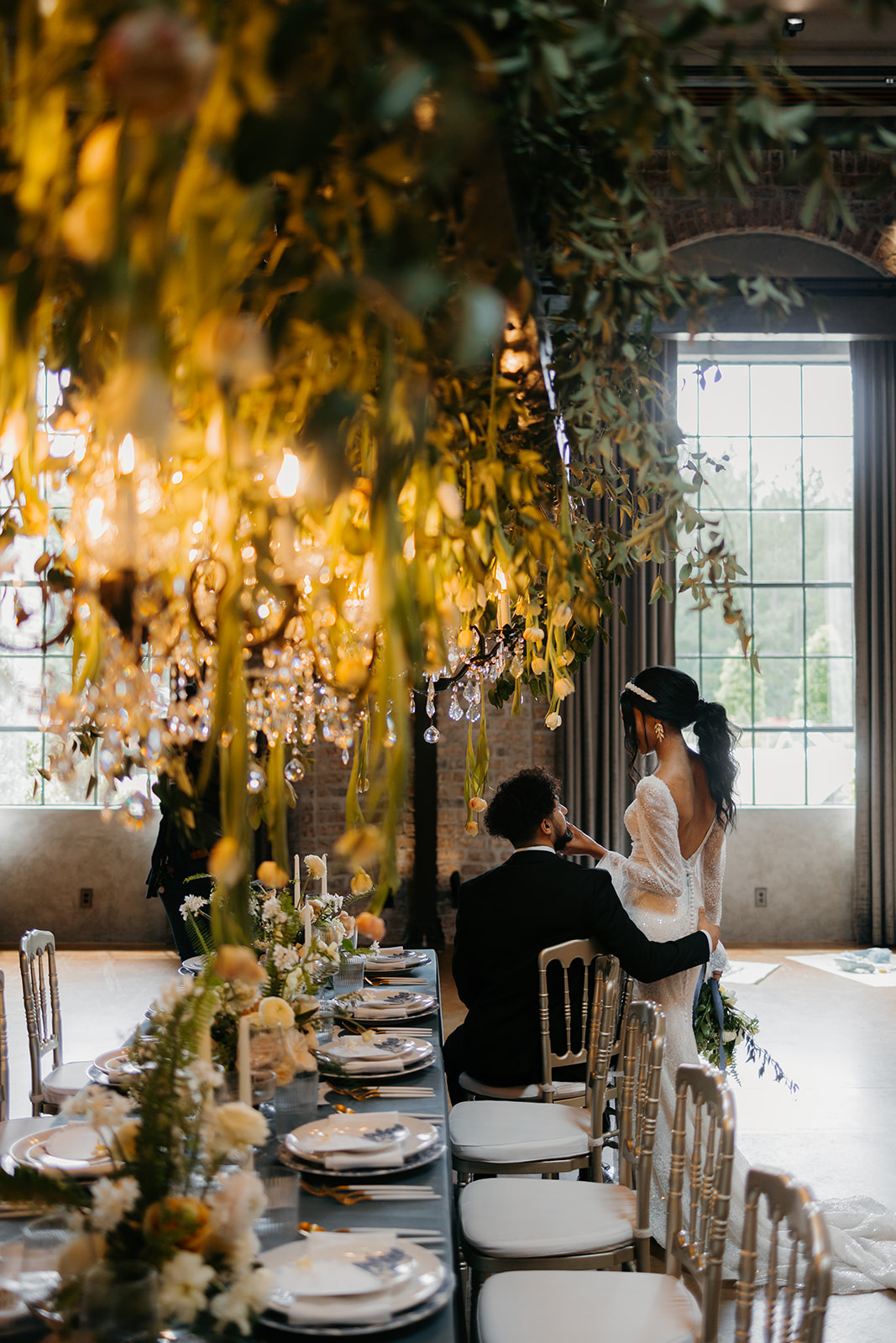 wedding couple by table covered in greenery